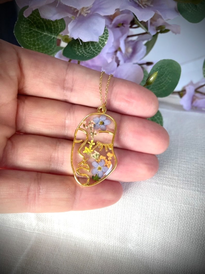 Pendant with abstract figure in resin and real flowers. Forget-me-not flowers, queen's lace. Woman face resin necklace