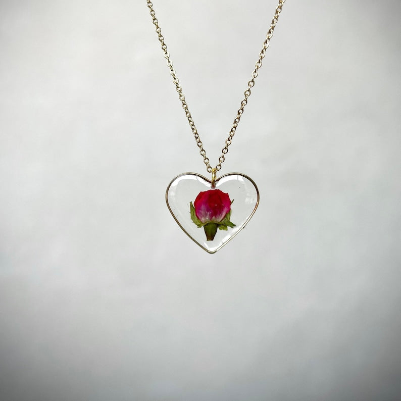 Complete this translation. Heart-shaped resin necklace with wild rose petals and gold leaves. Heart necklace with wild rose. Woman gift